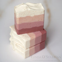 Load image into Gallery viewer, Three layered handmade soap bars stacked on a light marble surface. The top bar is upright, showing layers of off-white, dusty rose pink, and a deeper mauve-pink. Handmade in the UK by Linda O'Sullivan.