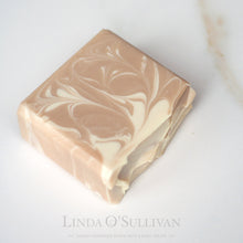 Load image into Gallery viewer, A bar of handmade soap with a beige and off-white marbled swirl pattern, photographed on a clean white background. Handmade in the UK by Linda O'Sullivan.